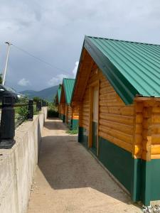 une rangée de bâtiments en bois avec un toit vert dans l'établissement Gusinje View, à Gusinje