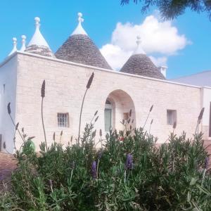 un edificio de ladrillo blanco con tres torretas en Trullo in vigna, en Cisternino