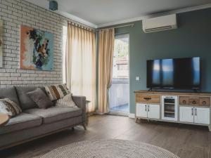 uma sala de estar com um sofá e uma televisão de ecrã plano em Stylish 1BD - Free Private Garage em Plovdiv