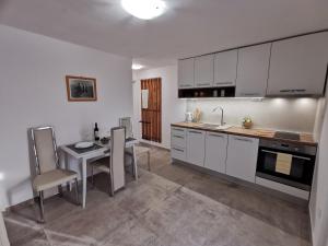 a kitchen with white cabinets and a table and chairs at Apartmani Vana in Tribunj