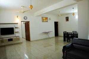 a living room with a television and a dining room at Crystal Villa Suite2 in Ernakulam