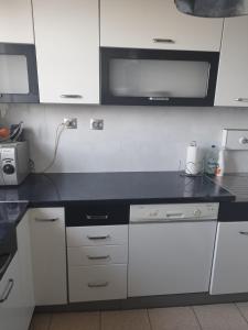 cocina con armarios blancos y encimera negra en Vip apart 2 en Gorlice