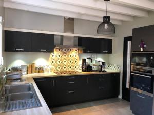 een keuken met zwarte kasten en een spoelbak bij Villa "OSTAU OCÉANE" in Capbreton