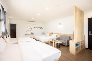 a white bedroom with two beds and a chair at 池上大地飯店 in Chishang