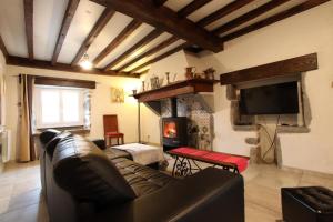 a living room with a leather couch and a fireplace at Bidainia in Ainhice-Mongelos