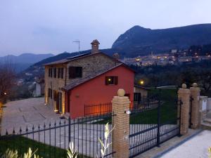 a house with a fence in front of a mountain at Country House Le Grazie in Serra San Quirico