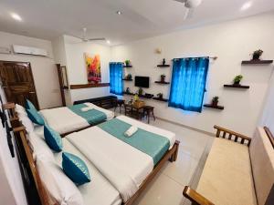 two beds in a room with blue curtains at THE LUXE HOTEL in Puducherry