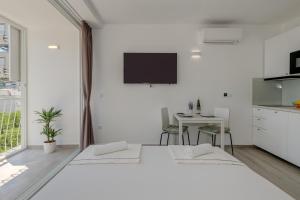 ein weißes Zimmer mit 2 Betten und einem Tisch in der Unterkunft Studio Apartment Anita with balcony in Split