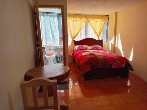 sypialnia z łóżkiem, stołem i oknem w obiekcie Hostal backpackers w mieście Chugchilán