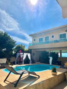 a swimming pool with a chair next to a house at Suítes Brandi in Arraial do Cabo +22 photos
