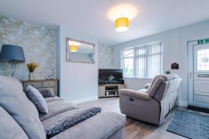a living room with a couch and a chair and a tv at 4 bed property, Bolton , Manchester in Egerton
