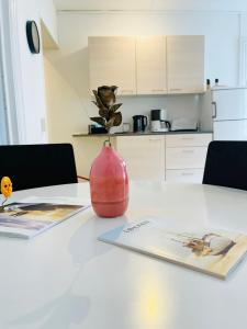 un vase rouge assis sur une table blanche avec deux menus dans l'établissement Scandinavian Apartment Hotel -Lunden 2- Central 2 room apartment, à Horsens