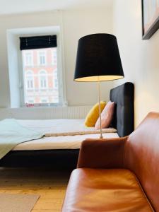 a bedroom with a bed with a lamp and a couch at Scandinavian Apartment Hotel -Lunden 2- Central 2 room apartment in Horsens