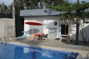 patio ze stołem i parasolem przy basenie w obiekcie l'avocatier w mieście Kenitra