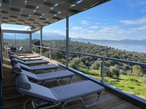 - une rangée de chaises longues sur une terrasse avec vue sur l'eau dans l'établissement Luxury Villa set in Idyllic Cove, sunets, dolphins Nr Lefkada Villa Levanda, à Spartos