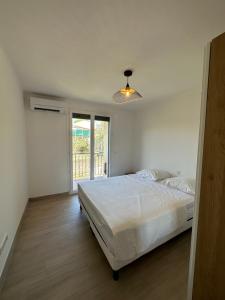 a white bedroom with a bed and a window at Alivu - Appartement Moderne Avec Terrasse in Cargèse