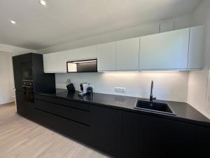 a kitchen with black and white cabinets and a sink at Alivu - Appartement Moderne Avec Terrasse in Cargèse +4 photos