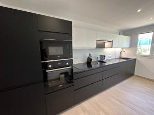 a kitchen with black cabinets and a microwave at Alivu - Appartement Moderne Avec Terrasse in Cargèse