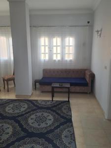 een kamer met een bank, een tafel en ramen bij ميرفيز هاوس Murphy's House in Hurghada