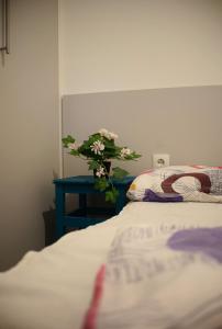 wazon kwiatów siedzący na stole obok łóżka w obiekcie Helikon 31 Apartman Keszthely w mieście Keszthely