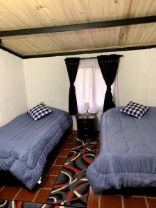 a bedroom with two beds and a window at Cabaña en la montaña de 3 Habitaciones in Sutatausa