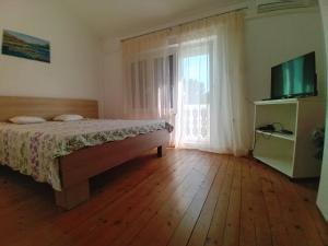 1 dormitorio con 1 cama, TV y ventana en Maestral, en Bribir