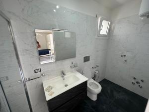 uma casa de banho com um lavatório, um WC e um espelho. em Infinity Residence con Parcheggio em Porto Cesareo