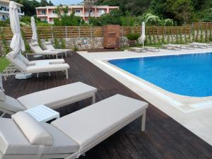 a pool with chaise lounge chairs and a swimming pool at Corfu valley view in Paleokastritsa