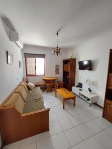 ein Wohnzimmer mit einem Bett und einem Tisch in der Unterkunft Apartamento Batalha - Quarteira, Algarve, Portugal in Quarteira