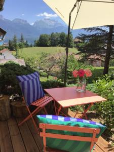 une table, une chaise et une table fleurie sur la terrasse dans l'établissement VUE LAC LODGES, à Sévrier