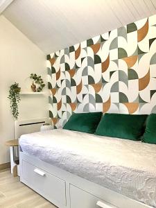 a bedroom with a bed with green pillows and a geometric wall at VUE LAC LODGES in Sévrier