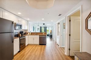 uma cozinha com armários brancos e piso em madeira em Sunset Vistas 407S em St. Pete Beach