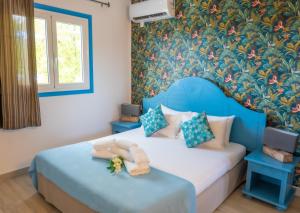 a bedroom with a blue bed and a floral wall at Résidence Vue Mer in Deshaies