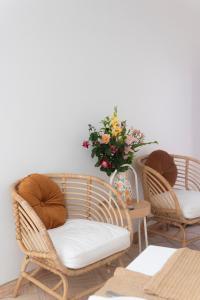 dos sillas de mimbre y una mesa con un jarrón de flores en A Casa de Cima - Cacela Velha, en Vila Nova de Cacela