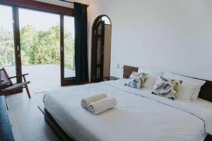 1 dormitorio con 1 cama blanca grande y ventana grande en Villa Gading, en Ubud