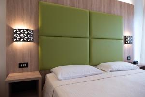 a bed with a green headboard in a room at Hotel St Gregory Park in Rimini