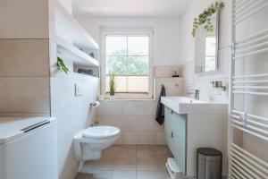 a white bathroom with a toilet and a sink at Appartments Am Goldberger See in Goldberg