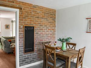 a dining room with a brick wall and a wooden table at No, 2 Badger Sett-uk44307 in Lenwade