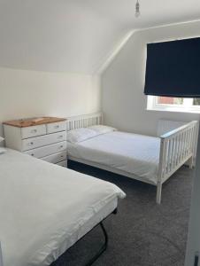 a bedroom with two beds and a dresser and a window at Sea Breeze Cottage Swanage Bay in Swanage