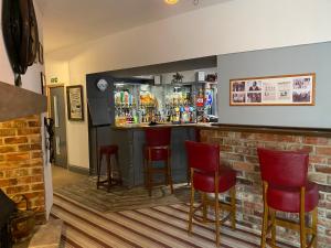 a bar with red chairs and a brick wall at The Crossroads Inn in Sacriston