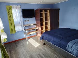 Schlafzimmer mit einem Bett und einem Flachbild-TV in der Unterkunft Cabañas y hostal Aurora in Castro