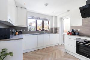 a kitchen with white cabinets and a large window at Stunning Five Bed Detached Home in Golden Valley