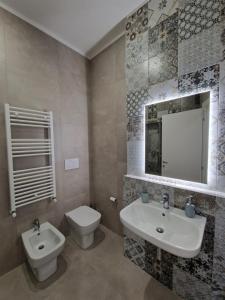 a bathroom with a sink and a toilet and a mirror at City Center Apartment in Termoli