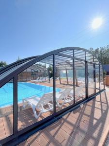 a glass house with a swimming pool and lounge chairs at Domki Zalesie in Jarosławiec