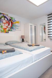 梅明根的住宿－#3 bequemes Zimmer mit Pool und Garten，白色客房的两张床,墙上挂有绘画作品