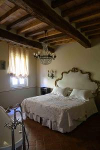 1 dormitorio con cama blanca y lámpara de araña en Villino di Porporano, en Parma