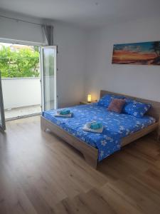 1 dormitorio con cama con sábanas azules y ventana en Apartment Valeria, en Lopar
