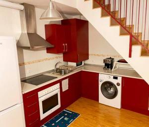 uma cozinha com armários vermelhos e uma máquina de lavar roupa em Acogedor Duplex en Malaga Centro em Málaga