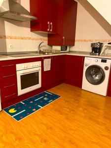 uma cozinha com armários vermelhos e uma máquina de lavar roupa em Acogedor Duplex en Malaga Centro em Málaga