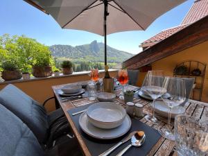 une table avec des assiettes, des verres et un parapluie dans l'établissement Bauernhof-Loft Edtgut, à Guggenthal